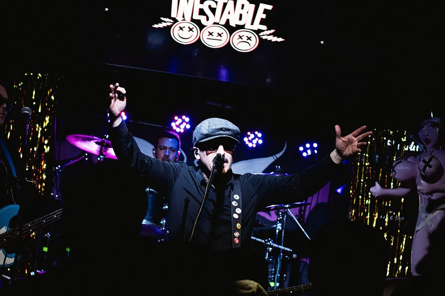 Vocalista con los brazos abiertos frente al logo